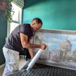 Person packing glassware into boxes with packing peanuts, preparing for relocation.